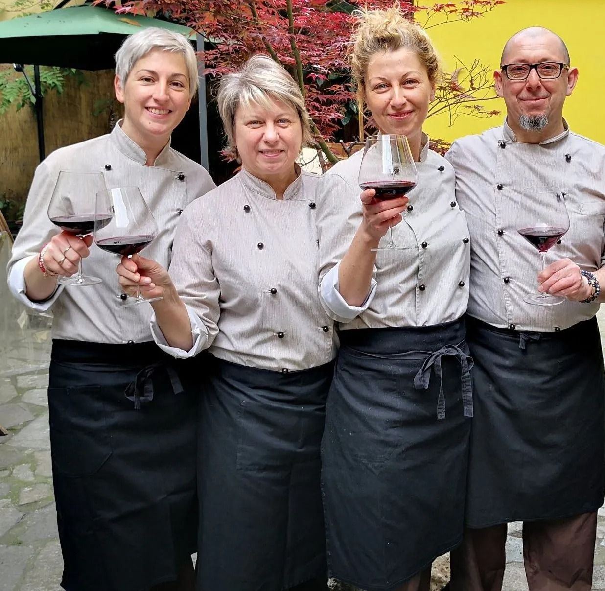 La brigata dell'Osteria Amarotto brinda con un bicchiere di rosso nel cortile